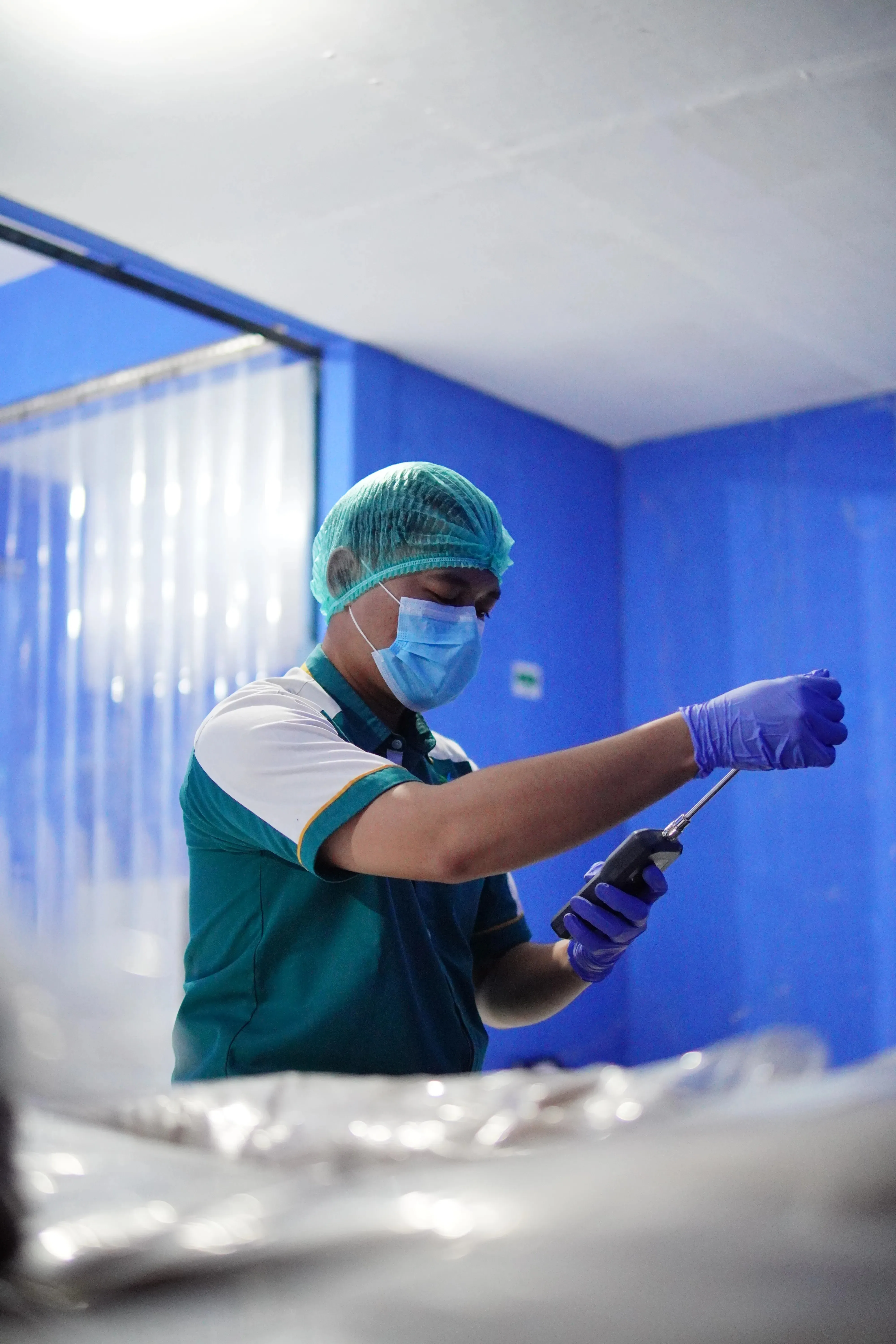 Javelo worker in a hairnet and gloves carrying a tray of coconut sugar from the drying rack